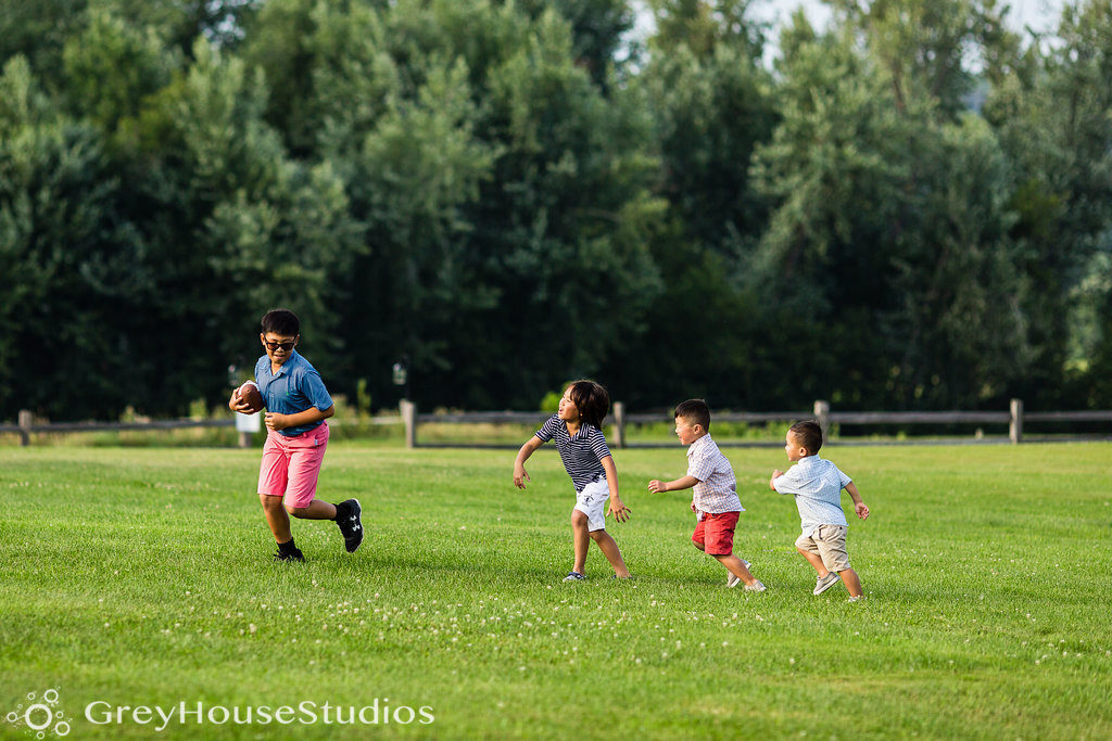 Four kids playing football in a field at an outdoor wedding venue in Vermont