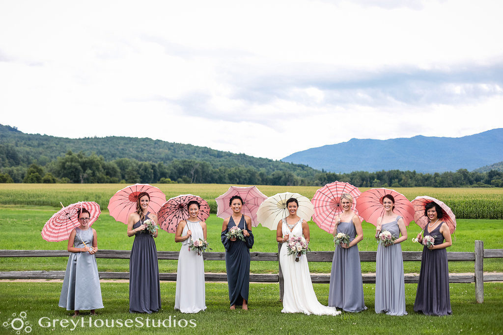 Bride and her bridesmaids standing together with pink umbrellas