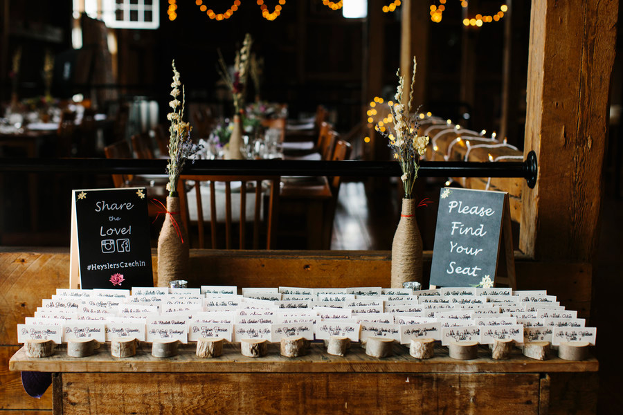 Wooden stump place card holders set out in The Barn at Boyden Farm's rustic wedding barn