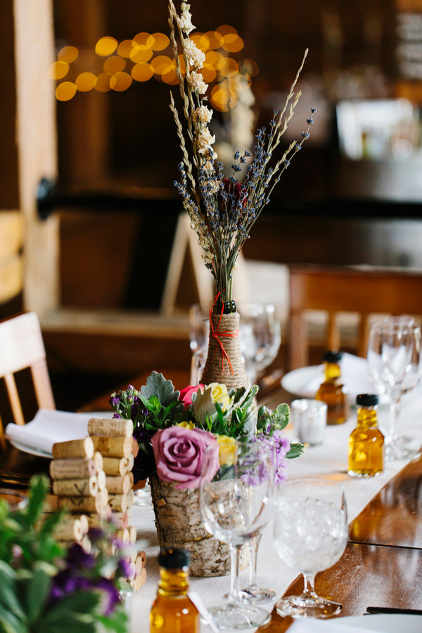 Tables set with flowers, glassware, and tiny maple syrup gifts for an elegant and rustic Vermont wedding