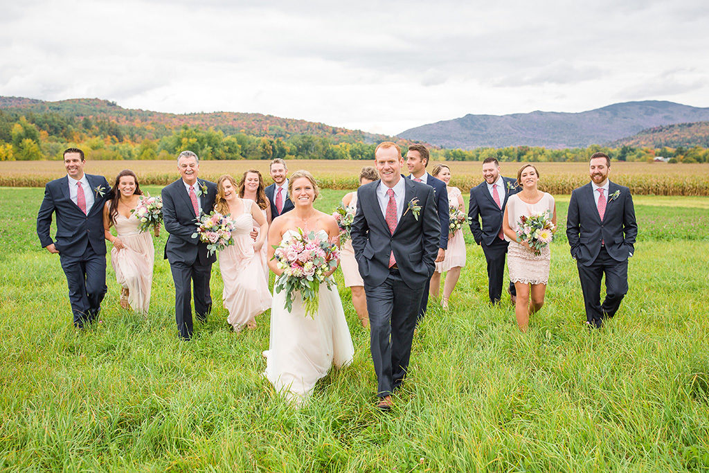 Married couple walking together with their wedding party outside at their Vermont fall wedding