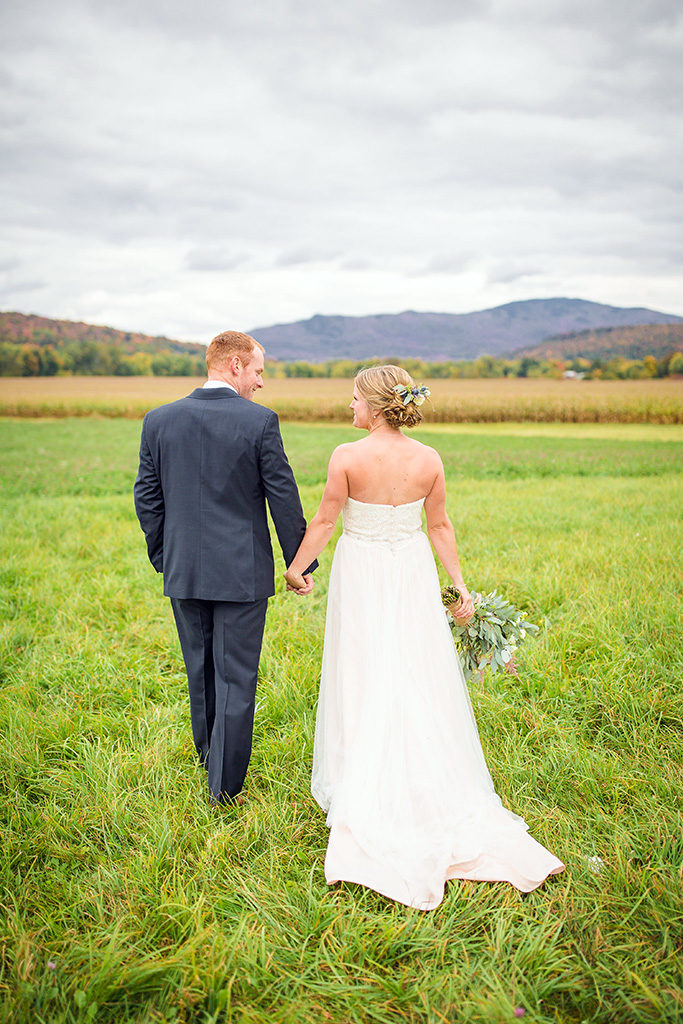 Newly married couple standing together facing the mountains at The Barn at Boyden Farm, their Vermont fall wedding venue