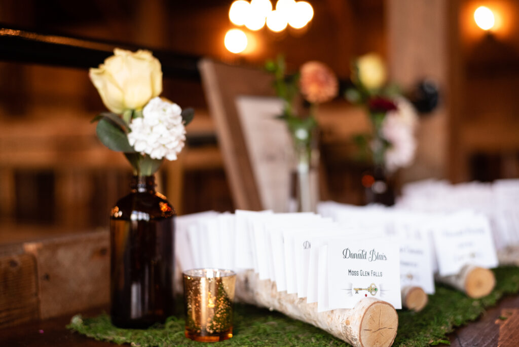 Flowers and wooden place card holders with names lined up in a row for a rustic wedding