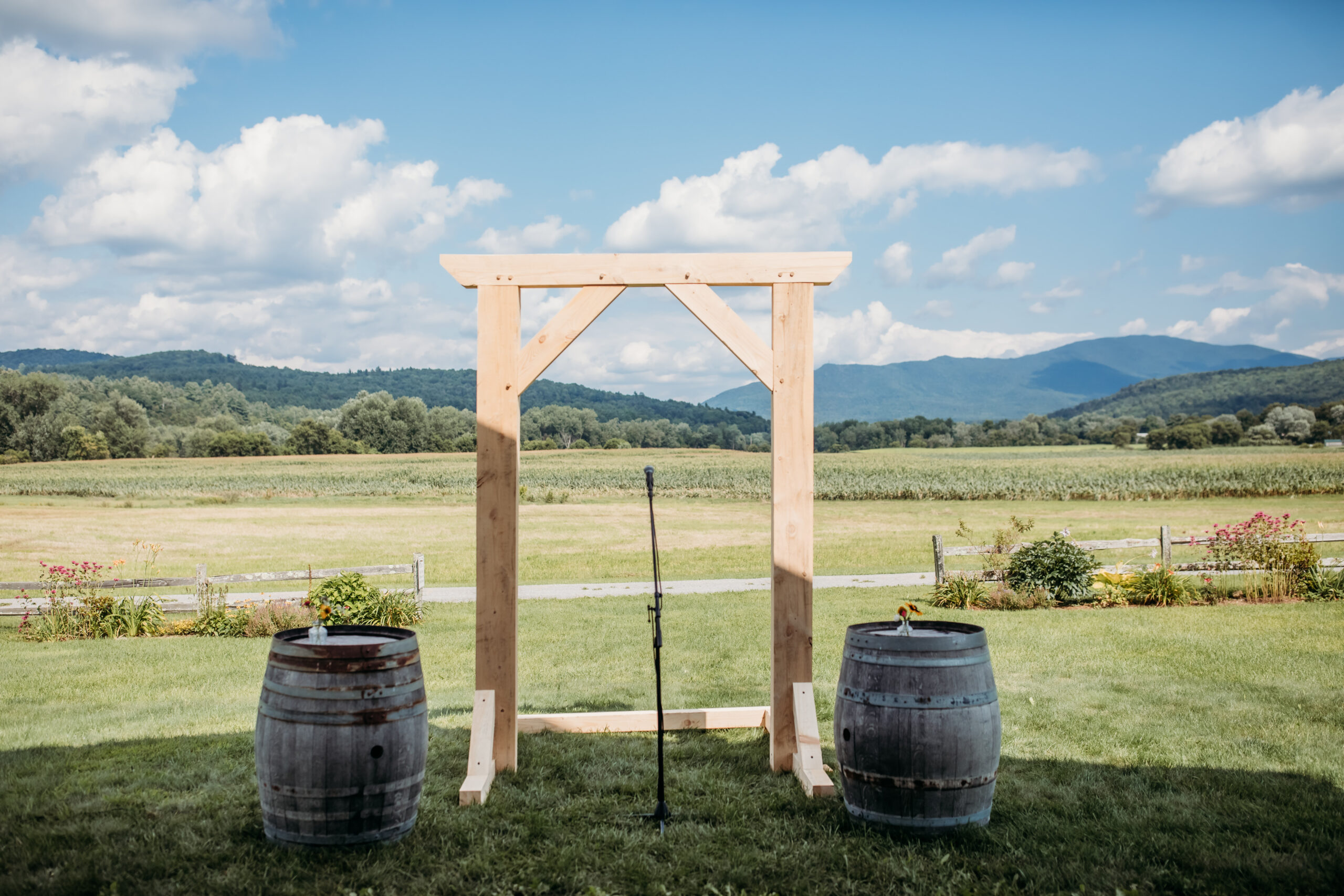 A simple, handcrafted wooden wedding arbor with rolling mountain views behind it at The Barn at Boyden Farm's summer wedding venue in Vermont