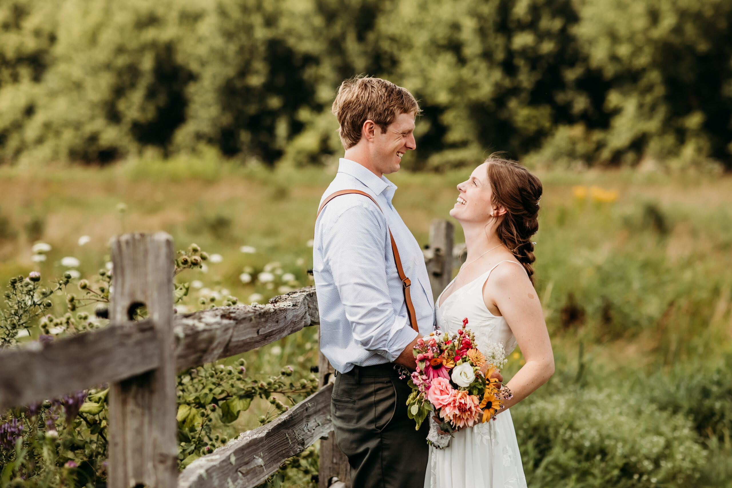Greg and Jess standing together against a fence after their wedding ceremony at their farm wedding venue