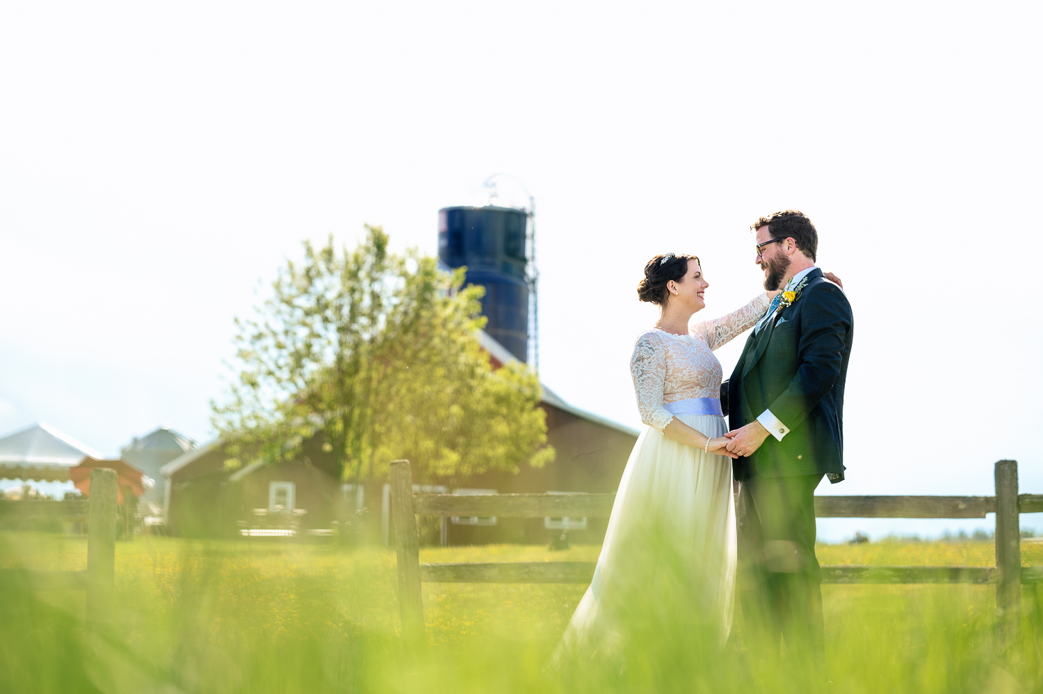 Anne and Jed standing together on their wedding day in front of The Barn at Boyden Farm's wedding barn