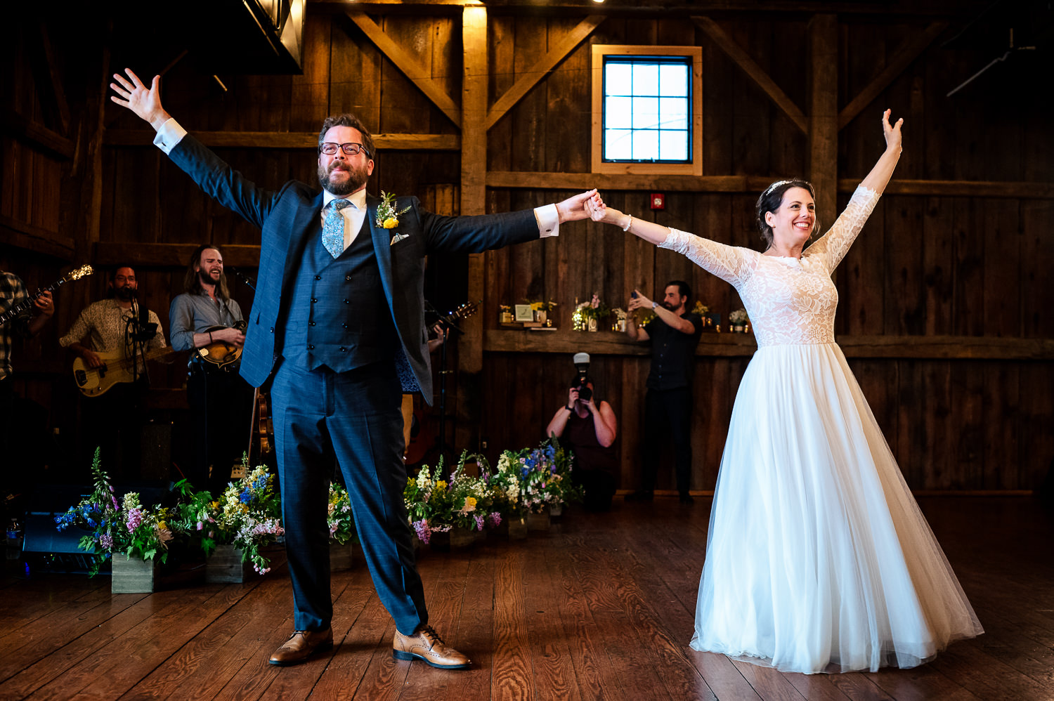 Anne and Jed holding hands on the dance floor of their Vermont wedding barn