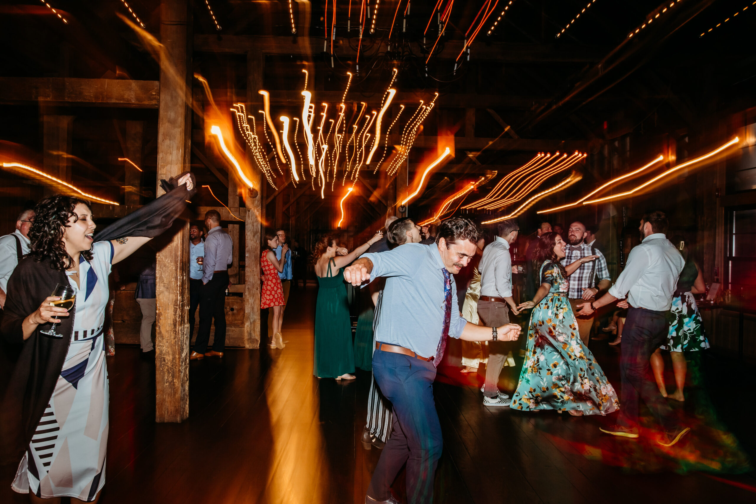 Guests dancing inside on the wedding barn's dancefloor