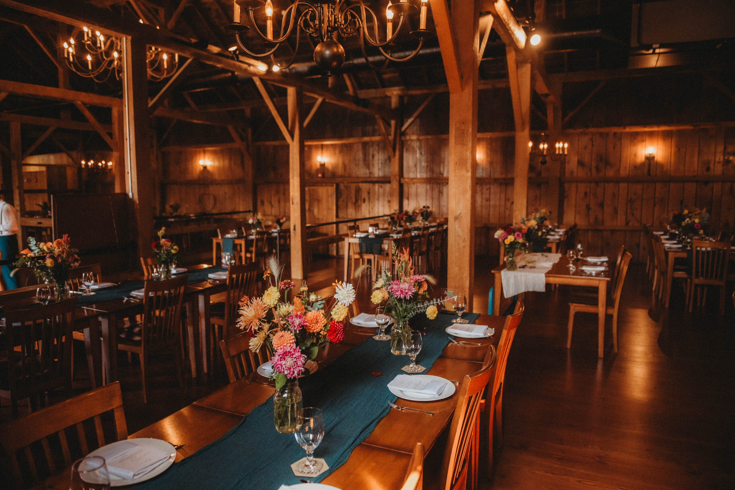 The barn interior decorated with pine green and fall florals for a rustic end of September wedding