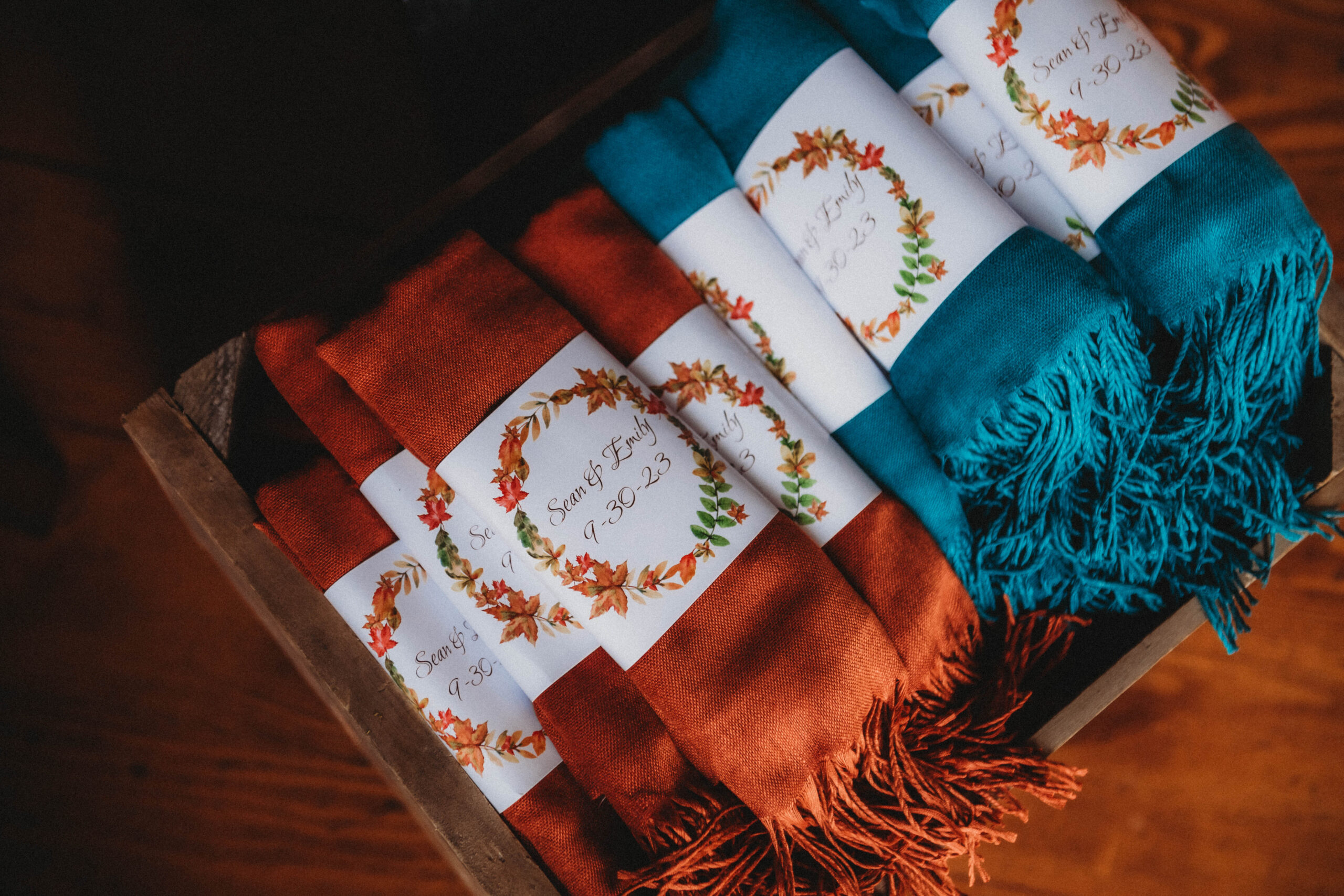 Rich orange and pine green scarves stacked together for guests to take home as wedding favors