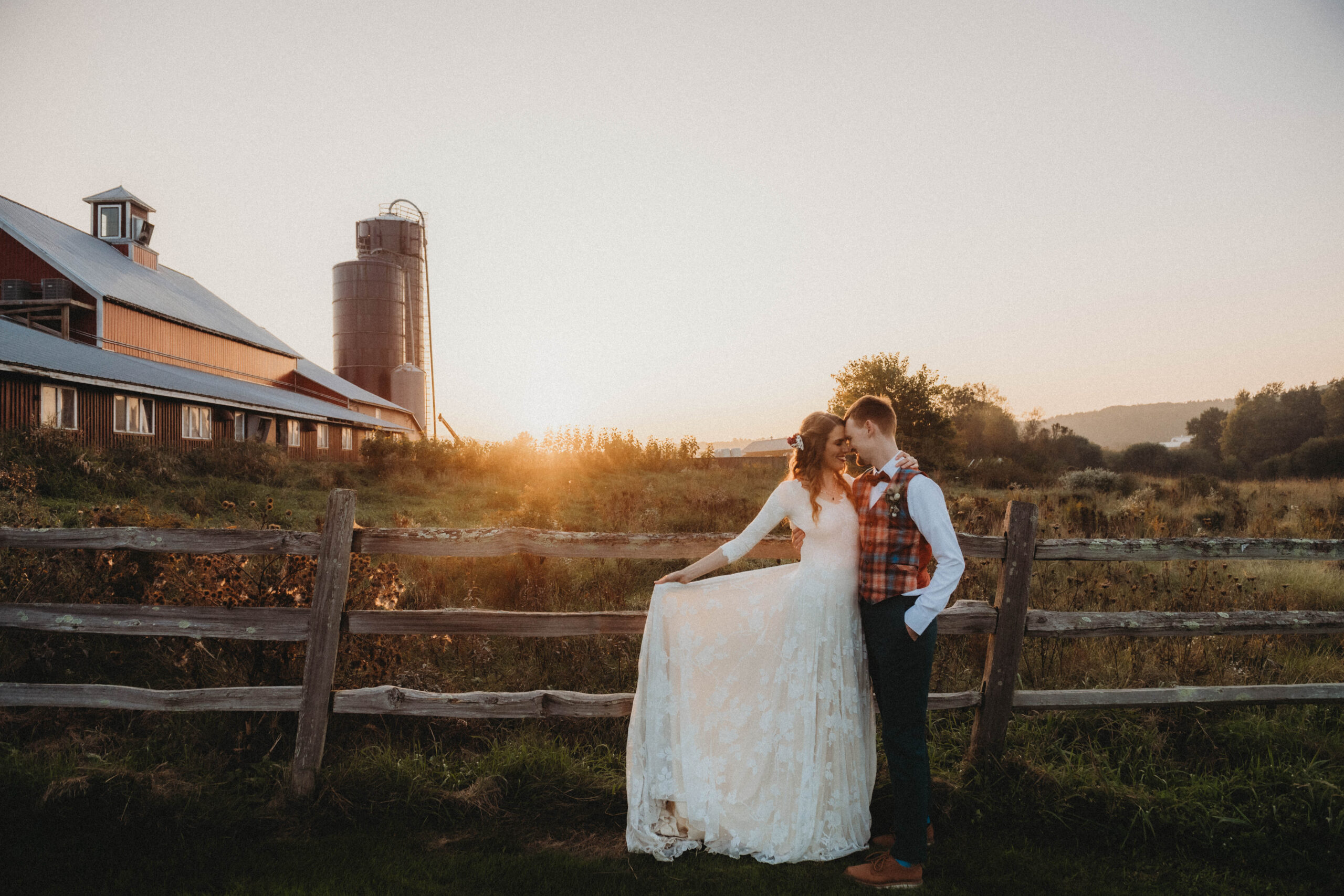 Emily and Sean standing together in front of the wedding barn at their farm wedding venue in Vermont