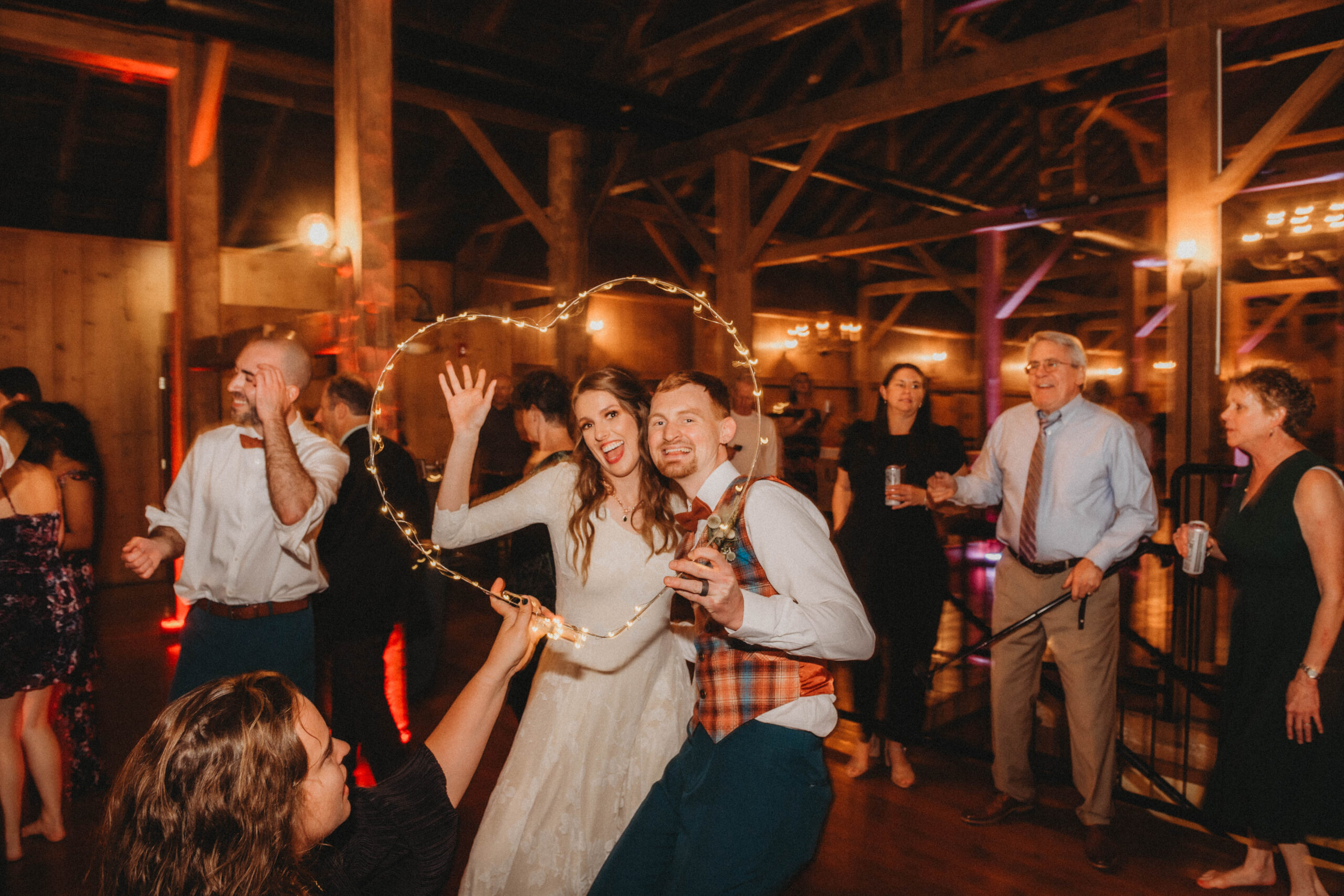 Emily and Sean together on the barn dance floor holding a string light heart