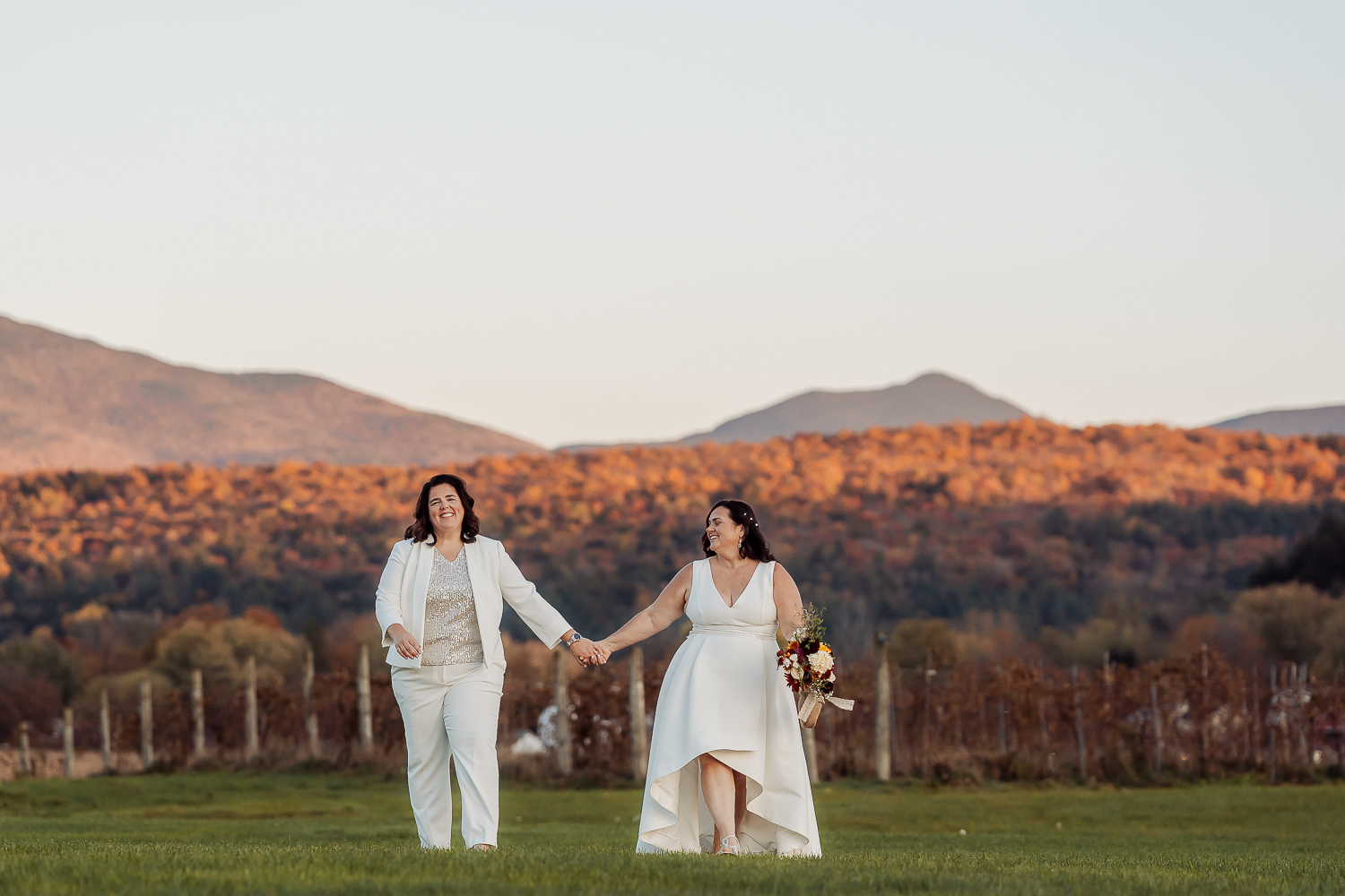 Darlene and Denise walking together with mountain views behind them at their outdoor October wedding