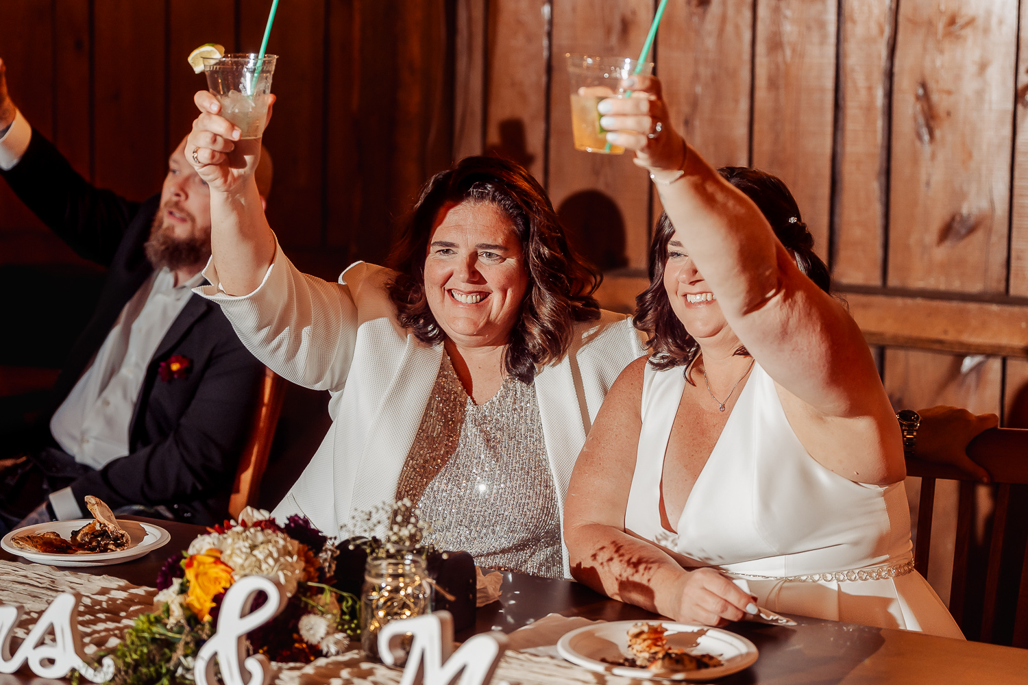 Darlene and Denise toasting everyone from their table in the wedding barn