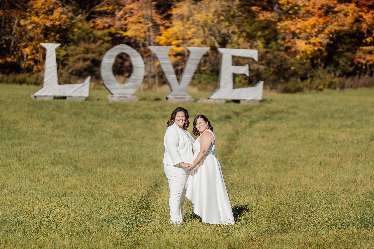 Denise and Darlene standing together in a field with large wooden letters spelling "Love" behind them